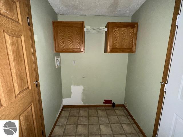 clothes washing area featuring laundry area, a textured ceiling, and baseboards