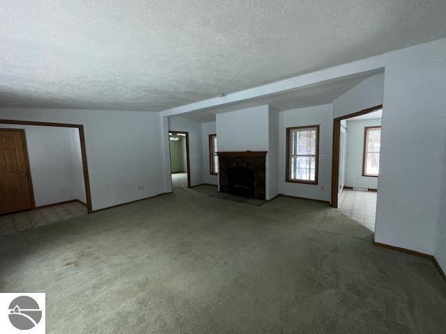 unfurnished living room with a fireplace with flush hearth, a textured ceiling, and carpet flooring