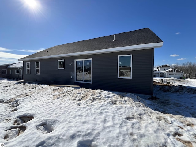 snow covered property featuring a shingled roof