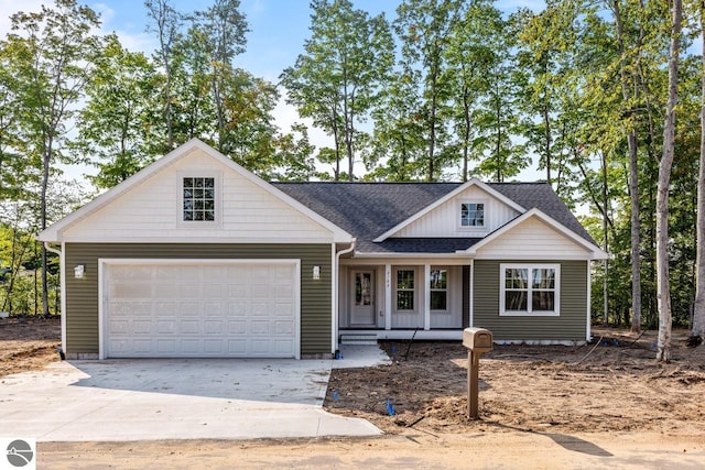 view of front facade with a shingled roof, concrete driveway, and a garage