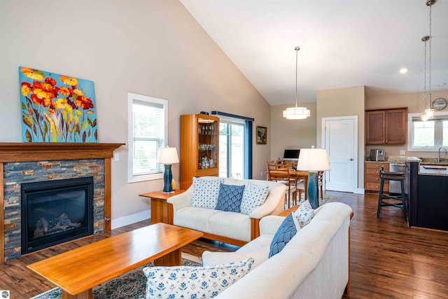 living room featuring recessed lighting, dark wood finished floors, a stone fireplace, baseboards, and high vaulted ceiling