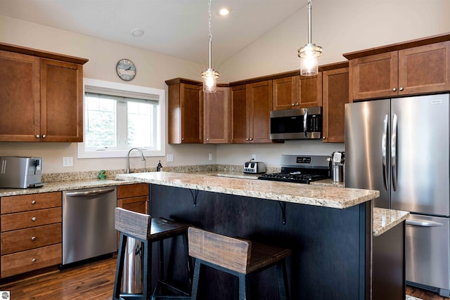 kitchen featuring stainless steel appliances, vaulted ceiling, a sink, a center island, and a breakfast bar area