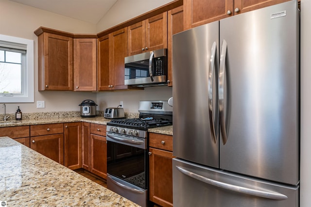 kitchen featuring stainless steel appliances, a sink, and brown cabinetry