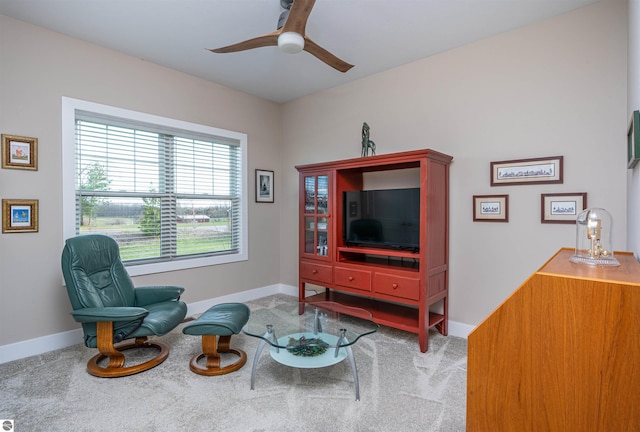 living area with a ceiling fan, baseboards, and carpet