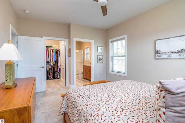 bedroom featuring light colored carpet, a ceiling fan, a closet, connected bathroom, and a walk in closet