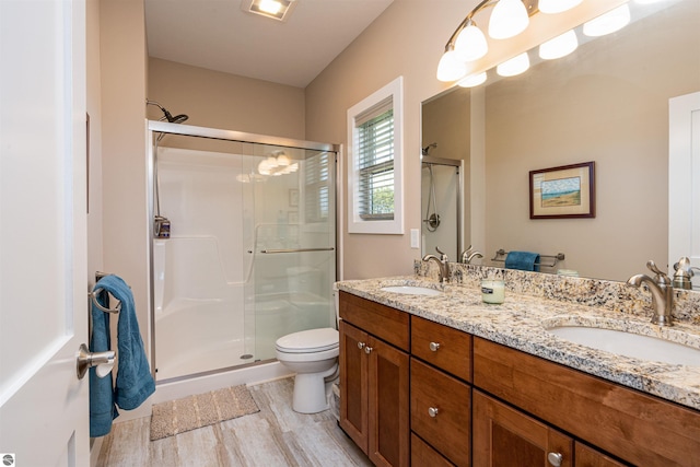 full bathroom with wood finished floors, a sink, a shower stall, and toilet