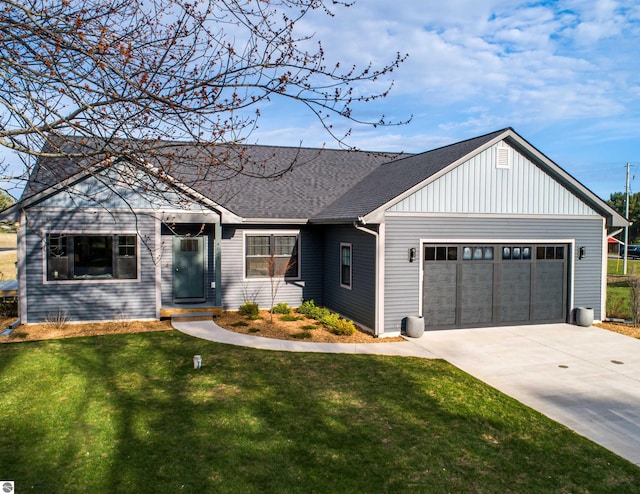 view of front of home featuring driveway, roof with shingles, a front yard, and a garage