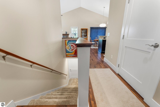 stairway with lofted ceiling, baseboards, and wood finished floors