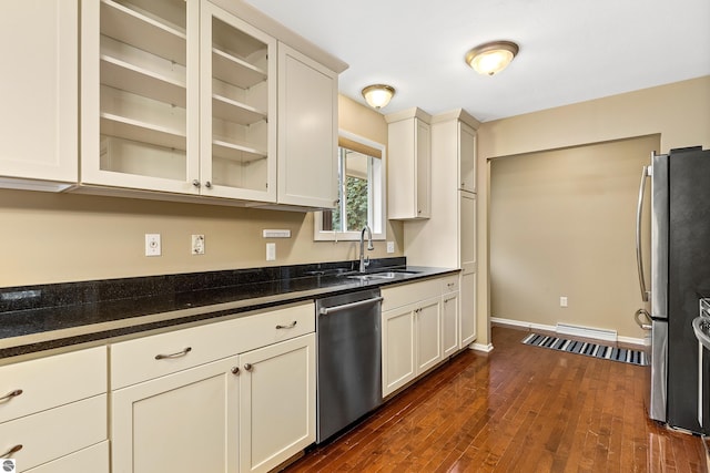 kitchen featuring baseboards, dark wood finished floors, glass insert cabinets, stainless steel appliances, and a sink