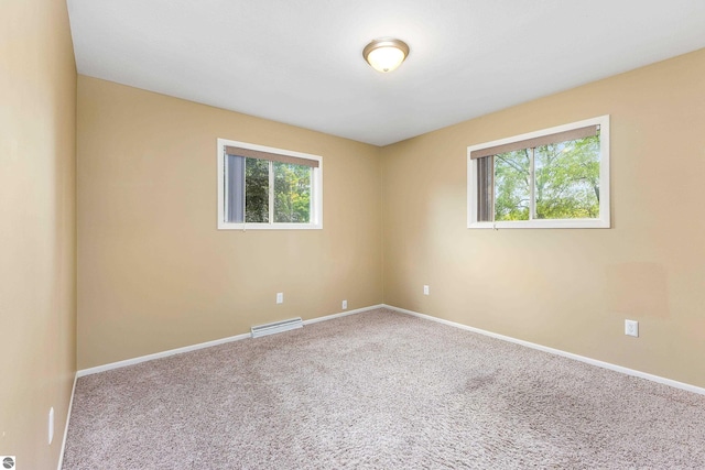 carpeted empty room featuring plenty of natural light, visible vents, and baseboards