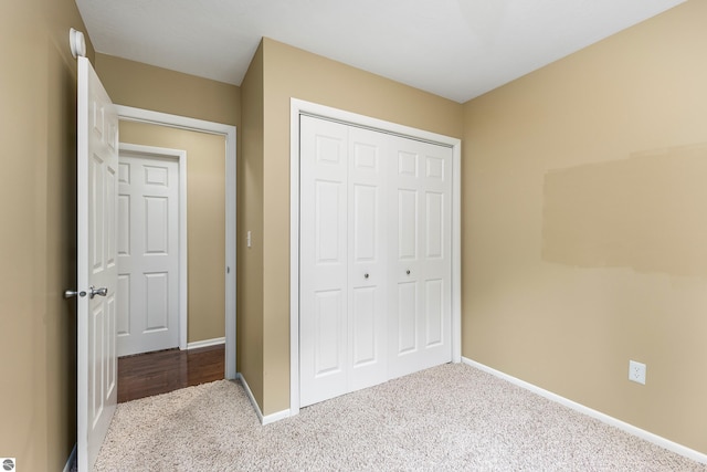 unfurnished bedroom with carpet floors, a closet, and baseboards