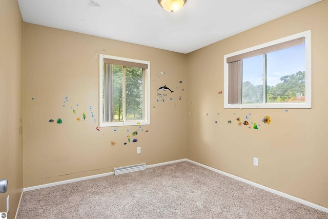 carpeted spare room featuring visible vents, plenty of natural light, and baseboards