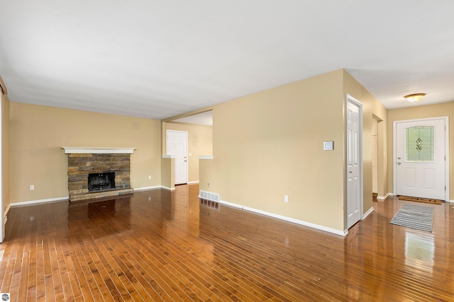 unfurnished living room with baseboards, visible vents, a fireplace, and hardwood / wood-style floors