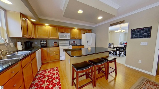 kitchen with white appliances, a sink, tasteful backsplash, a kitchen bar, and crown molding