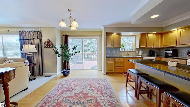 kitchen with crown molding, dark countertops, decorative backsplash, a healthy amount of sunlight, and a kitchen bar