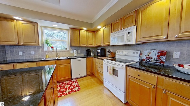 kitchen featuring dark stone counters, white appliances, backsplash, and a sink