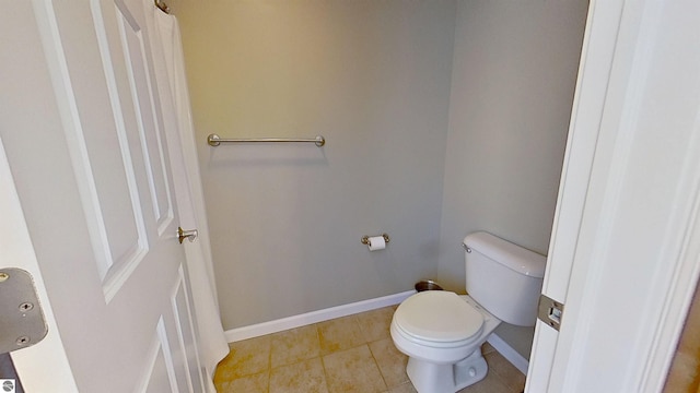 bathroom with toilet, baseboards, and tile patterned floors