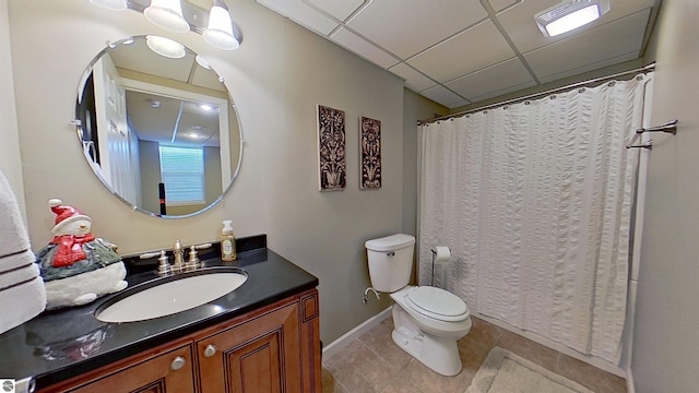 full bathroom with toilet, vanity, a drop ceiling, baseboards, and tile patterned floors