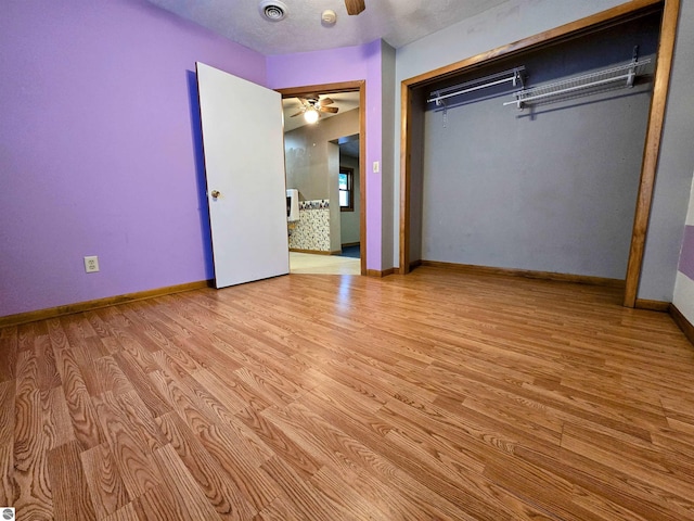 unfurnished bedroom with a closet, wood finished floors, visible vents, and baseboards