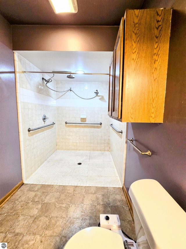 bathroom with baseboards, a tile shower, and toilet