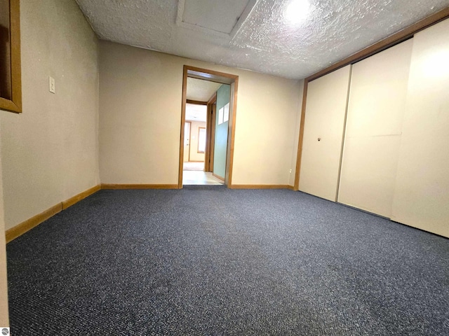 empty room featuring carpet, baseboards, and a textured ceiling