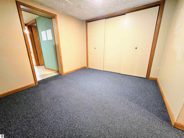 unfurnished bedroom with carpet floors, a closet, a textured ceiling, and baseboards