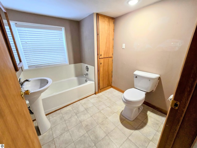 bathroom featuring toilet, baseboards, and a bath