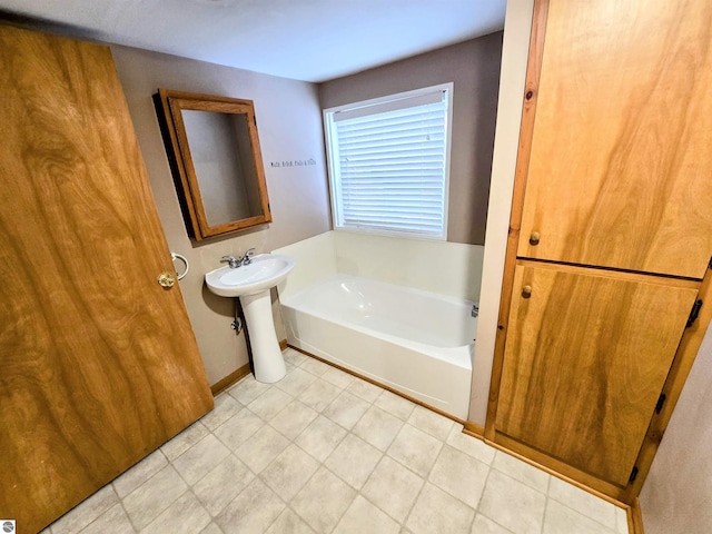 bathroom featuring a sink, a garden tub, and baseboards