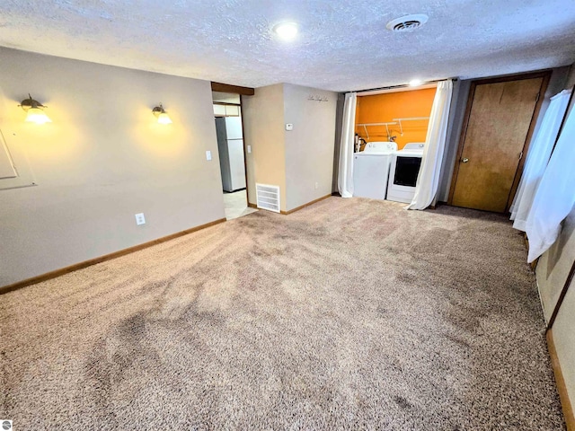 interior space with baseboards, visible vents, a textured ceiling, and washing machine and clothes dryer