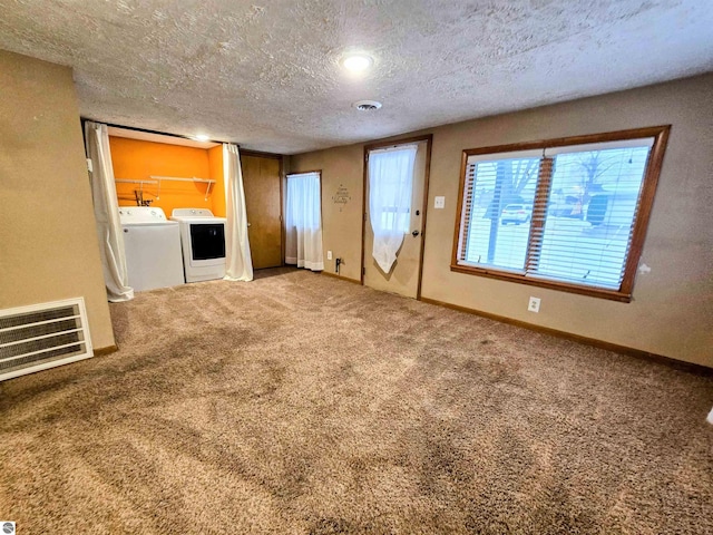 unfurnished living room featuring a textured ceiling, visible vents, baseboards, carpet, and washing machine and clothes dryer