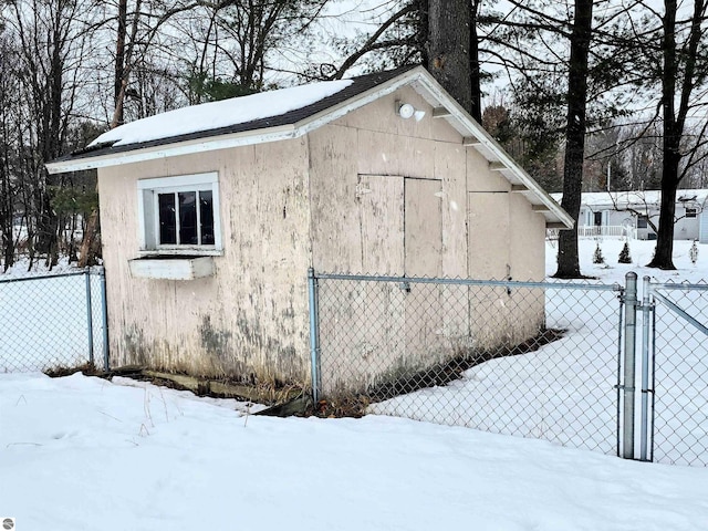 snow covered structure featuring a gate and fence