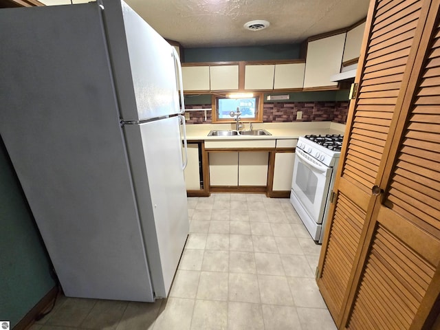 kitchen featuring light countertops, visible vents, a sink, white appliances, and exhaust hood