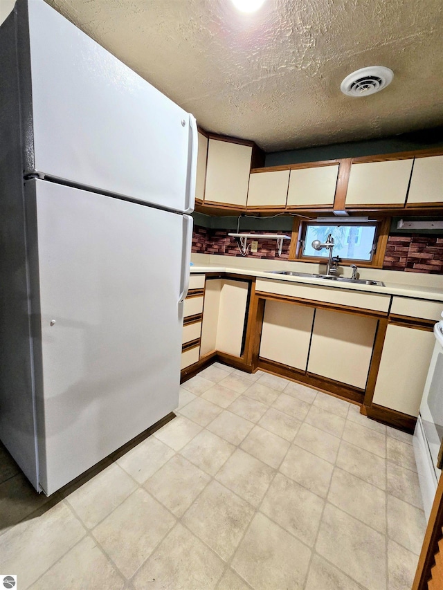 kitchen featuring a sink, visible vents, white cabinetry, light countertops, and freestanding refrigerator