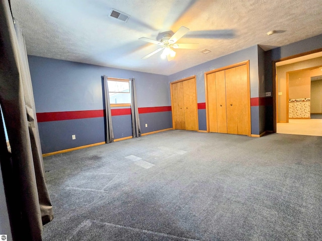 unfurnished bedroom featuring baseboards, visible vents, carpet, a textured ceiling, and multiple closets