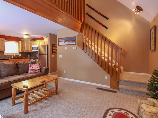 living area with a high ceiling, light carpet, stairway, and baseboards