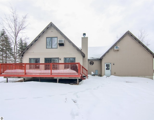 snow covered back of property featuring a deck and a chimney