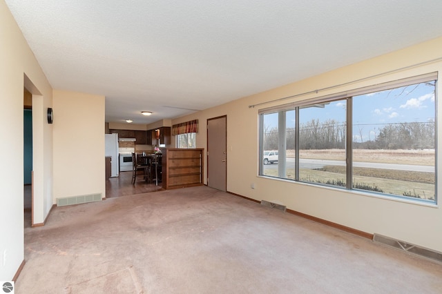 unfurnished living room featuring light carpet, visible vents, and baseboards