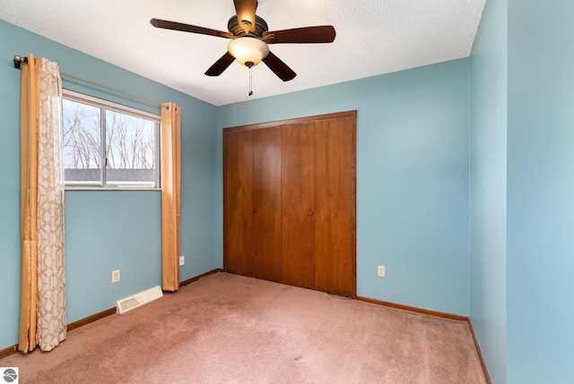 unfurnished bedroom featuring a closet, visible vents, carpet flooring, ceiling fan, and baseboards