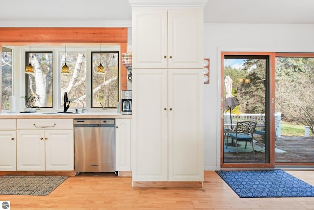 kitchen with a sink, white cabinets, light wood-style floors, light countertops, and stainless steel dishwasher