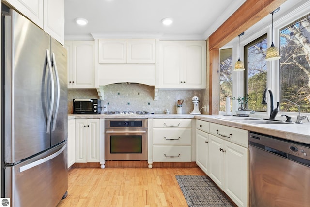 kitchen featuring a toaster, light wood-style flooring, appliances with stainless steel finishes, light countertops, and a sink