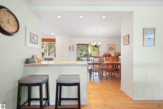 kitchen featuring light wood-type flooring, white cabinetry, plenty of natural light, and a breakfast bar area