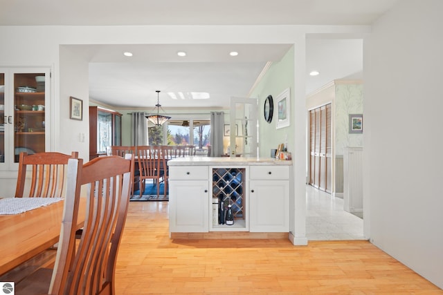 kitchen featuring wine cooler, light wood finished floors, light countertops, ornamental molding, and white cabinets