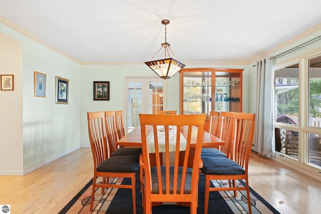 dining room with light wood-type flooring, baseboards, ornamental molding, and french doors