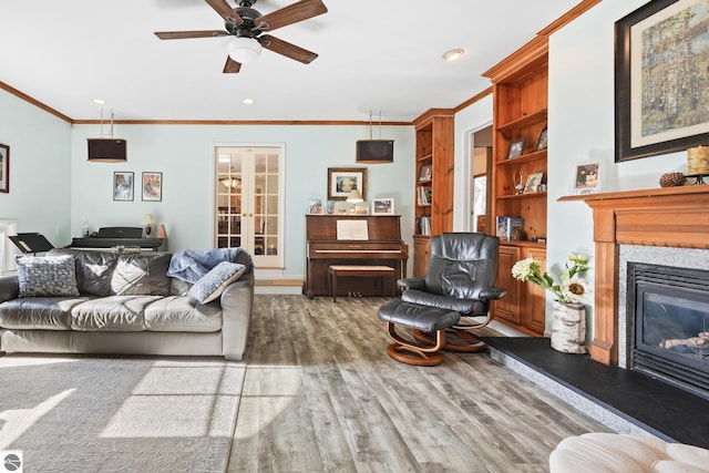 living room with a premium fireplace, wood finished floors, a ceiling fan, french doors, and crown molding