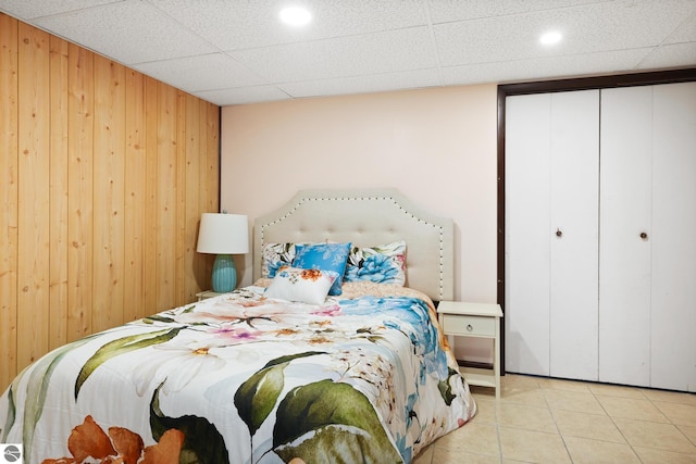 tiled bedroom with a paneled ceiling and wooden walls