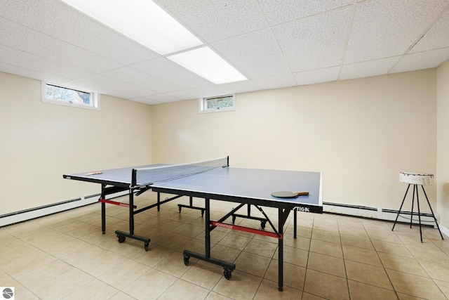 rec room with a baseboard radiator, tile patterned flooring, and a paneled ceiling