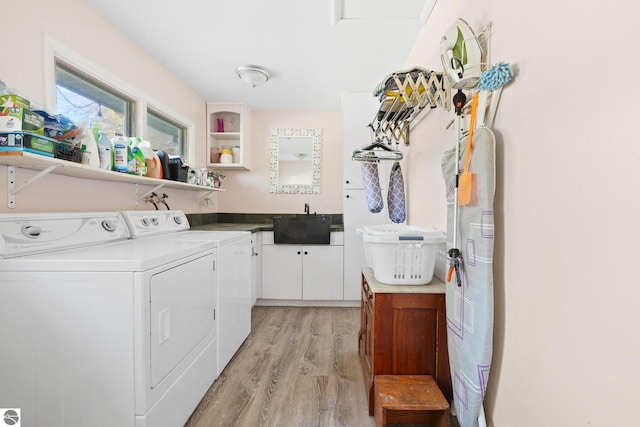 laundry area featuring a sink, light wood-type flooring, washing machine and clothes dryer, and cabinet space