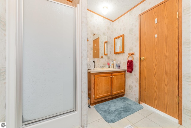 full bathroom with vanity, a shower with shower door, wallpapered walls, a textured ceiling, and crown molding