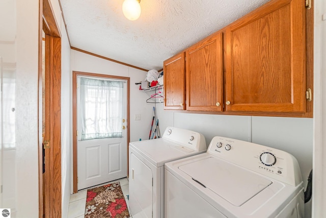 clothes washing area with light tile patterned flooring, cabinet space, a textured ceiling, and independent washer and dryer