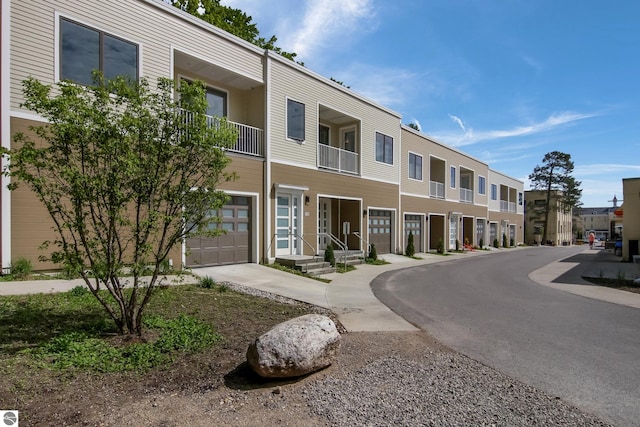 view of building exterior featuring a garage, driveway, and a residential view